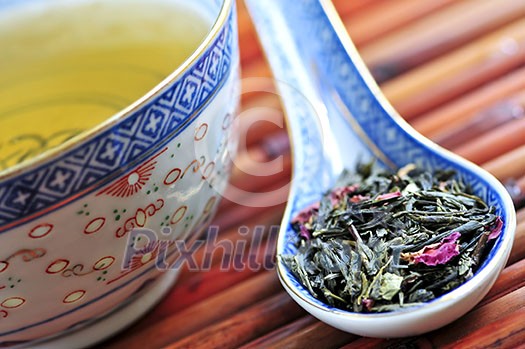Cup of green tea with loose dry leaves in a spoon Cup of green tea with loose dry leaves in a spoon
