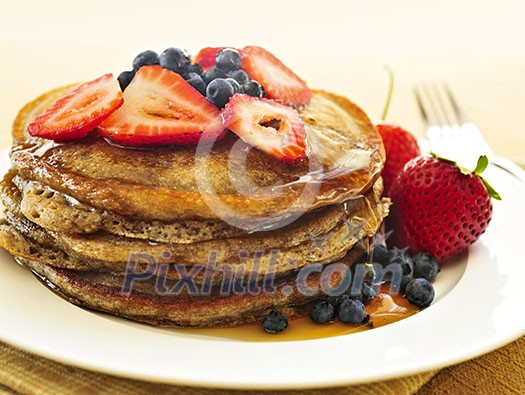 Stack of buckwheat pancakes with fresh berries and maple syrup Stack of buckwheat pancakes with fresh berries and maple syrup
