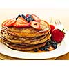 Stack of buckwheat pancakes with fresh berries and maple syrup