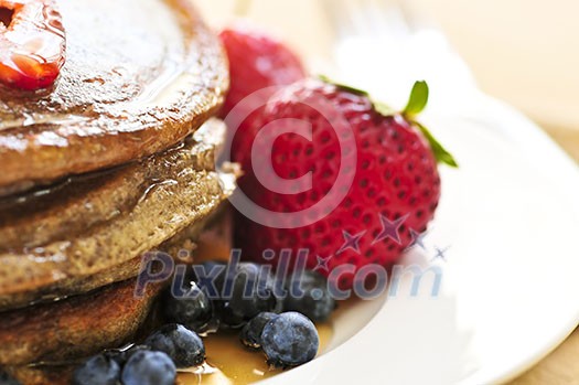 Stack of buckwheat pancakes with fresh berries and maple syrup Stack of buckwheat pancakes with fresh berries and maple syrup