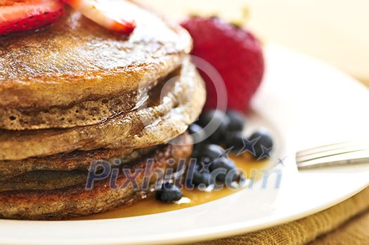 Stack of buckwheat pancakes with fresh berries and maple syrup Stack of buckwheat pancakes with fresh berries and maple syrup