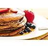 Stack of buckwheat pancakes with fresh berries and maple syrup