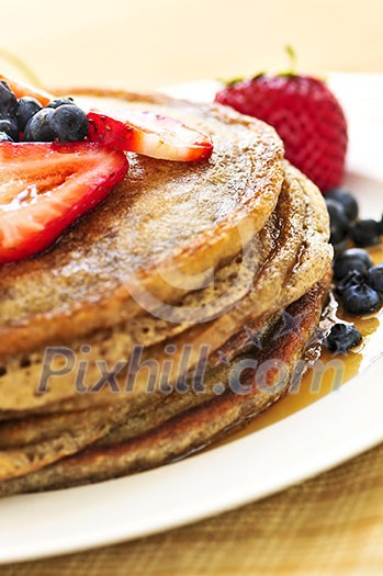 Stack of buckwheat pancakes with fresh berries and maple syrup Stack of buckwheat pancakes with fresh berries and maple syrup