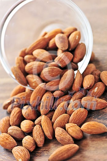Raw almonds spilling out of small glass bowl Raw almonds spilling out of small glass bowl