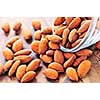 Raw almonds spilling out of small glass bowl