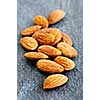 Raw almonds in a pile on wooden surface