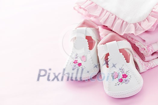 Infant girl clothing and shoes for baby shower on pink background Infant girl clothing and shoes for baby shower on pink background