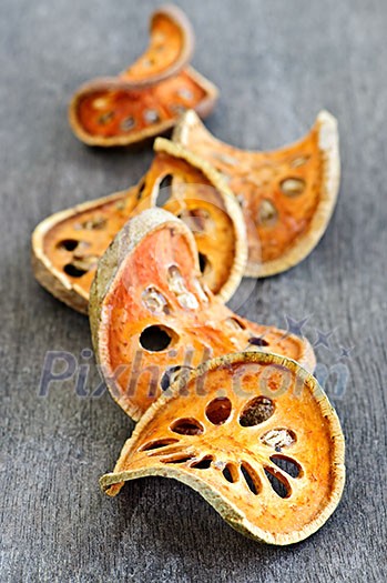 Slices of dried bael fruit on wood surface Slices of dried bael fruit on wood surface