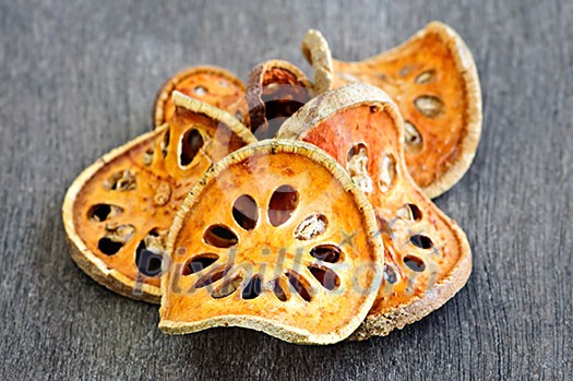 Slices of dried bael fruit on wood surface Slices of dried bael fruit on wood surface