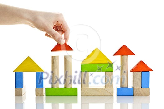 Hand building houses of wooden block toys isolated on white background Hand building houses of wooden block toys isolated on white background