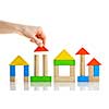 Hand building houses of wooden block toys isolated on white background