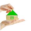 Hand holding green wooden block house isolated on white