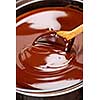 Wooden spoon stirring soft melted rich chocolate