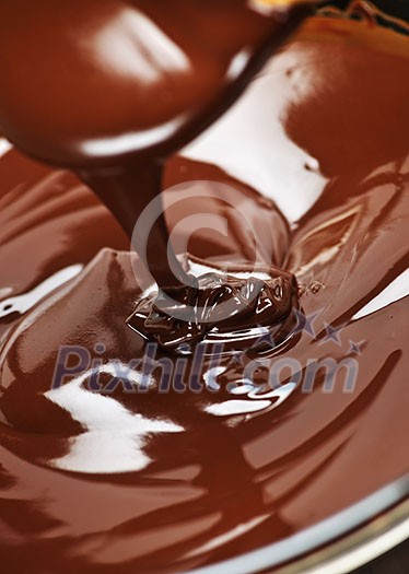 Melted rich dark chocolate dripping from spoon Melted rich dark chocolate dripping from spoon