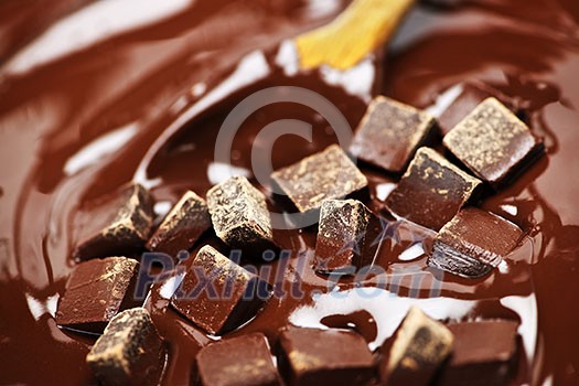 Wooden spoon stirring melting rich chocolate chunks Wooden spoon stirring melting rich chocolate chunks