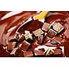 Wooden spoon stirring melting rich chocolate chunks