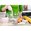 Pouring sugar into mixing bowl with ingredients for making cookies