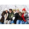 Group of diverse young friends showing thumbs up outdoors in winter