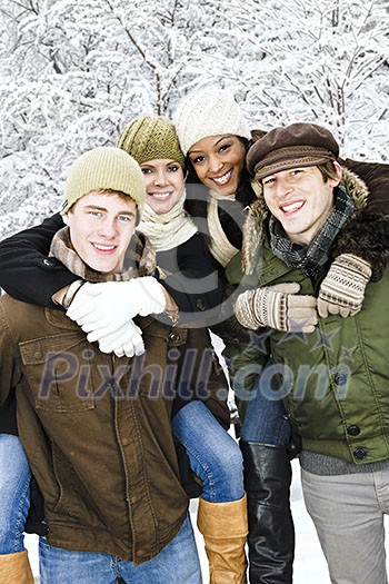 Group of young friends giving piggy back rides outdoors in winter Group of young friends giving piggy back rides outdoors in winter