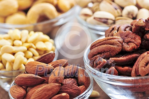 Many glass bowls of almonds walnuts pistachios and pine nuts Many glass bowls of almonds walnuts pistachios and pine nuts