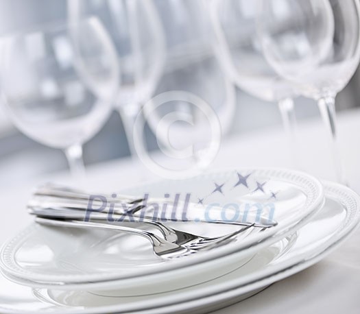 Elegant restaurant table setting with plates cutlery and stemware Elegant restaurant table setting with plates cutlery and stemware