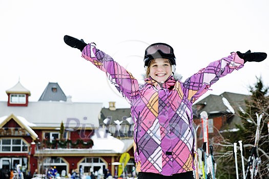 Happy teenage girl with arms raised in ski helmet at winter resort Happy teenage girl with arms raised in ski helmet at winter resort