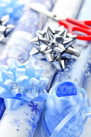Rolls of Christmas wrapping paper with ribbons, bows and scissors Rolls of Christmas wrapping paper with ribbons, bows and scissors
