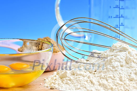 Flour, whisk and eggs in a bowl, baking ingredients Flour, whisk and eggs in a bowl, baking ingredients