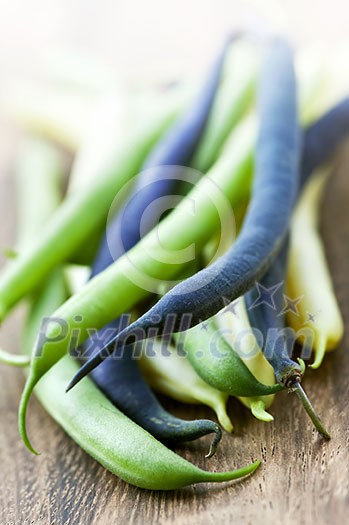 Pile of purple yellow and green string beans on cutting board Pile of purple yellow and green string beans on cutting board