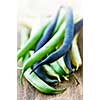 Pile of purple yellow and green string beans on cutting board