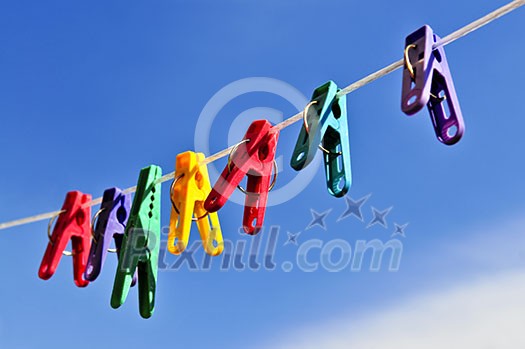Colorful clothes pegs on line against blue sky Colorful clothes pegs on line against blue sky