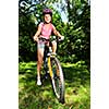 Portrait of a teenage girl on a bicycle in summer park outdoors