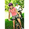 Teenage girl and her father riding bicycles in summer park
