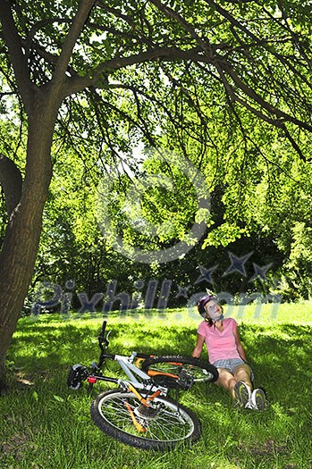 Teenage girl relaxing under green tree with her bicycle Teenage girl relaxing under green tree with her bicycle