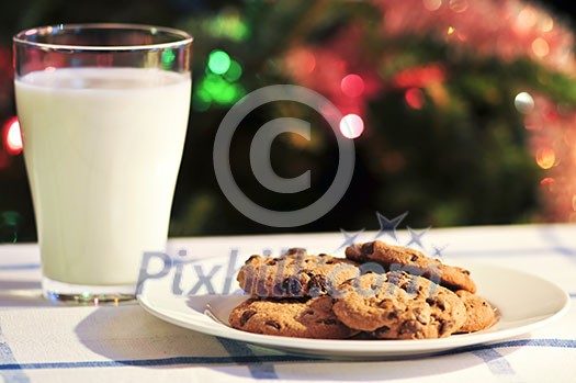 Plate of cookies and glass of milk near Christmas tree Plate of cookies and glass of milk near Christmas tree