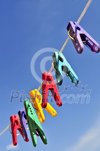 Colorful clothes pegs on line against blue sky Colorful clothes pegs on line against blue sky