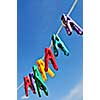 Colorful clothes pegs on line against blue sky