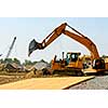 Yellow bulldozer machines digging and moving earth at construction site