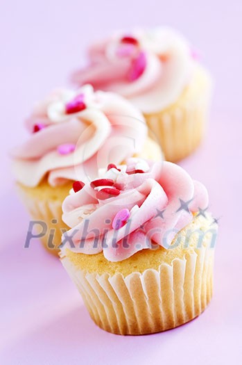 Row of tasty cupcakes with icing and sprinkles Row of tasty cupcakes with icing and sprinkles