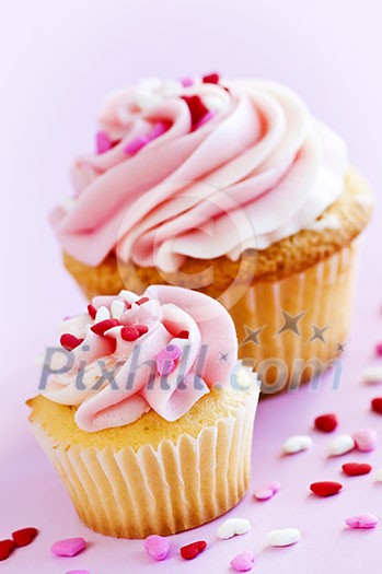 Big and small cupcakes with icing and sprinkles Big and small cupcakes with icing and sprinkles