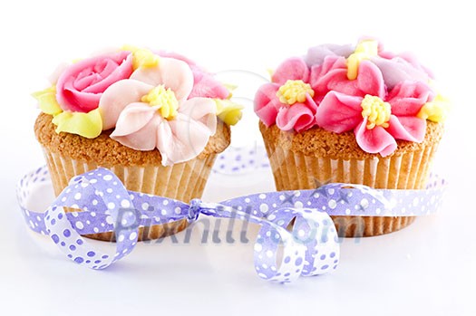 Pair of cupcakes with icing flowers and ribbon