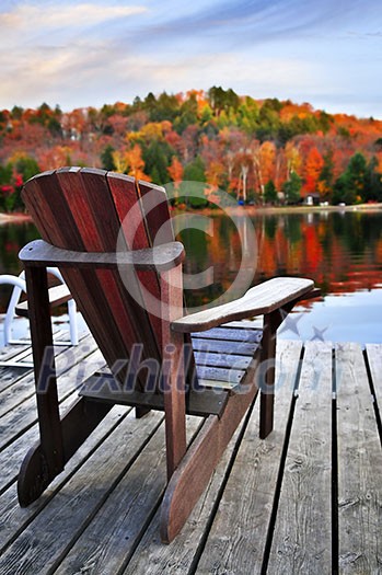 Wooden dock with chair on calm fall lake Wooden dock with chair on calm fall lake