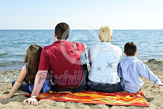 Family sitting on towel at sandy beach Family sitting on towel at sandy beach