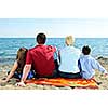 Family sitting on towel at sandy beach