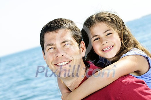 Portrait of father giving piggyback ride to daughter at seashore Portrait of father giving piggyback ride to daughter at seashore