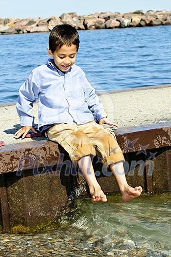 Portrait of young boy dipping feet in lake from pier Portrait of young boy dipping feet in lake from pier