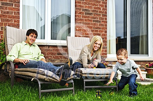 Happy family relaxing in backyard of new home with toddler Happy family relaxing in backyard of new home with toddler