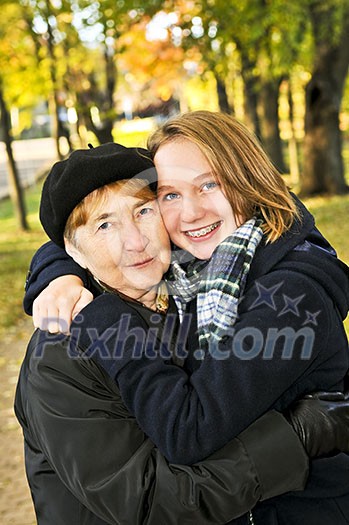 Teen granddaughter hugging grandmother in autumn park Teen granddaughter hugging grandmother in autumn park