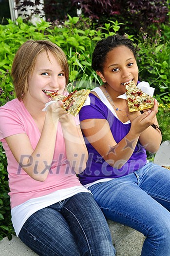 Two teenage girls sitting and eating pizza Two teenage girls sitting and eating pizza