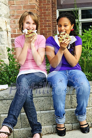 Two teenage girls sitting and eating pizza Two teenage girls sitting and eating pizza